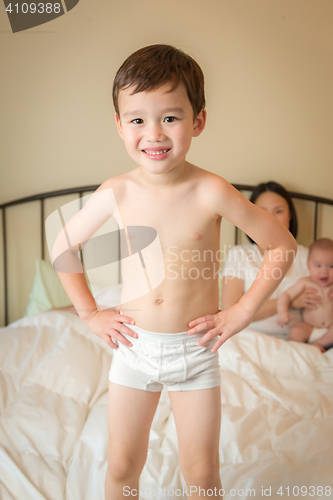 Image of Mixed Race Chinese and Caucasian Boy Jumping In Bed with His Fam