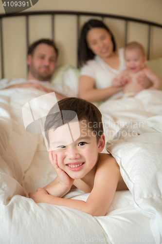 Image of Mixed Race Chinese and Caucasian Boy Laying In Bed with His Fath