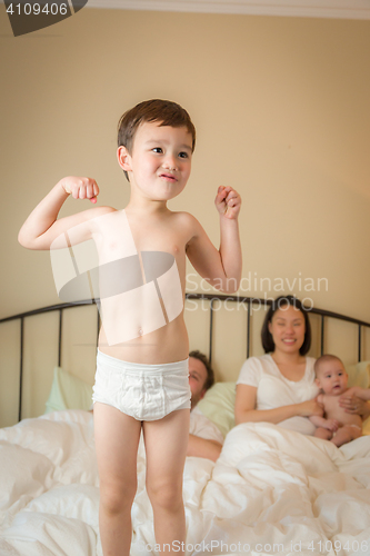 Image of Mixed Race Chinese and Caucasian Boy Jumping In Bed with His Fam