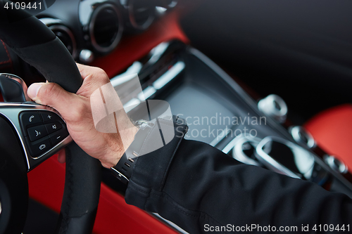 Image of Male driver hands holding steering wheel.