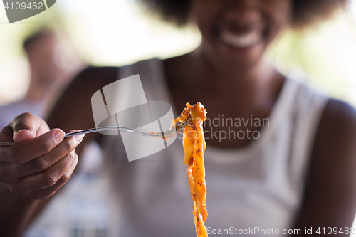 Image of a young African American woman eating pasta