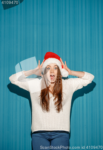 Image of Surprised christmas girl wearing a santa hat