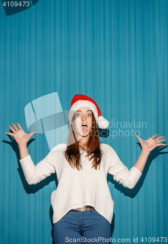 Image of Surprised christmas girl wearing a santa hat