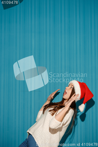 Image of Surprised christmas girl wearing a santa hat