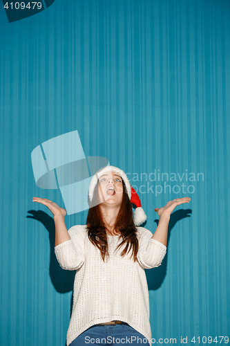 Image of Surprised christmas girl wearing a santa hat