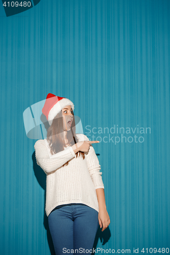 Image of Surprised christmas girl wearing a santa hat
