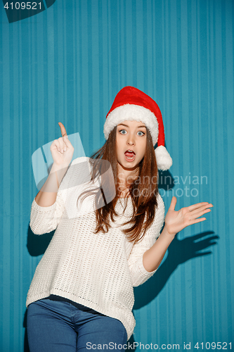 Image of Surprised christmas girl wearing a santa hat