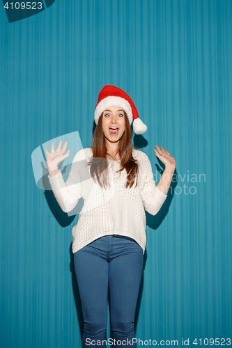 Image of Surprised christmas girl wearing a santa hat