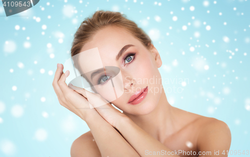 Image of beautiful young woman face and hands over snow
