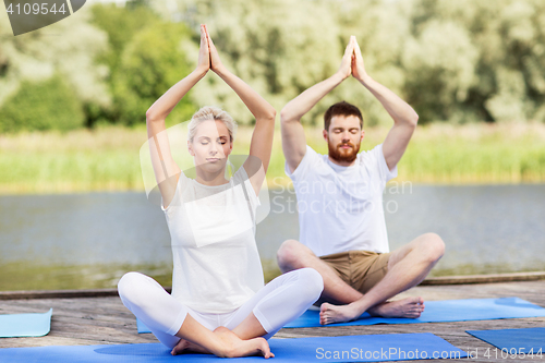 Image of people meditating in yoga lotus pose outdoors