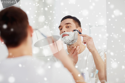 Image of man shaving beard with razor blade at bathroom