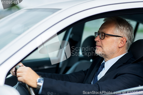 Image of happy senior businessman driving car