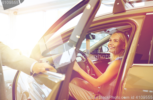 Image of happy woman with car dealer in auto show or salon