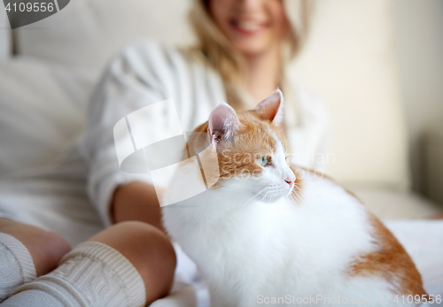 Image of happy young woman with cat in bed at home