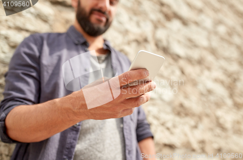 Image of close up of man with smartphone at stone wall