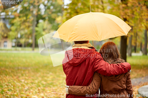 Image of happy couple with umbrella walking in autumn park