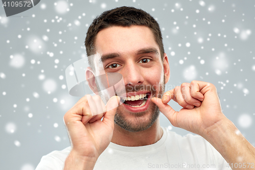 Image of man with dental floss cleaning teeth over snow