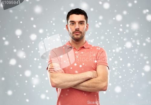 Image of young man with crossed arms over snow background