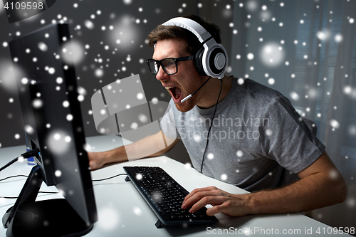 Image of man in headset playing computer video game at home