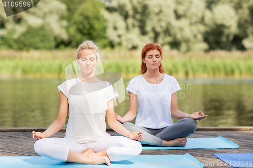 Image of women meditating in yoga lotus pose outdoors