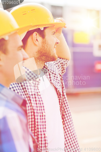 Image of group of smiling builders in hardhats outdoors