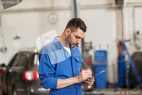 Image of auto mechanic man with clipboard at car workshop