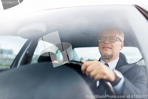 Image of happy senior businessman driving car