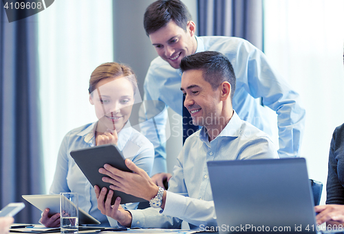 Image of smiling business people with tablet pc in office