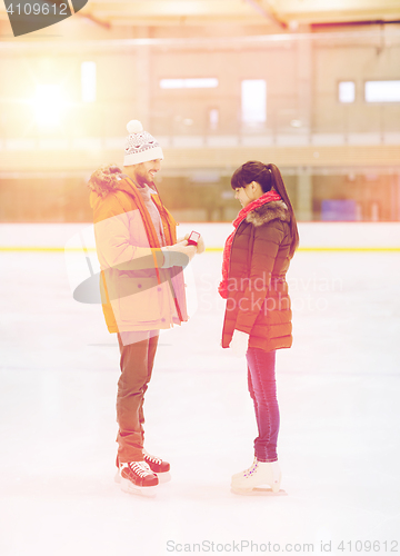 Image of happy couple with engagement ring on skating rink