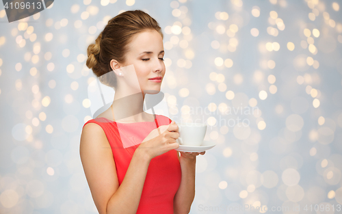 Image of woman in red with cup of coffee over lights