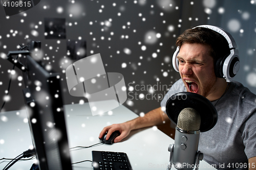 Image of man in headset playing computer video game at home