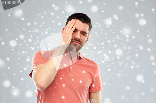 Image of unhappy man suffering from head ache over snow