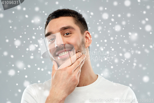 Image of happy young man touching his face or beard