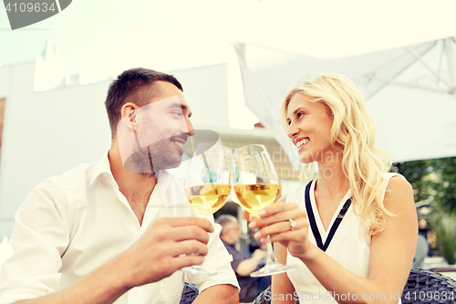 Image of happy couple drinking wine at open-air restaurant