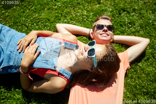 Image of happy teenage couple lying on grass at summer