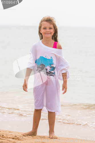 Image of Cheerful girl basking on the beach wearing a large T-shirt parent