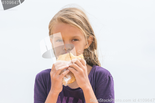 Image of A hungry girl with an appetite chews delicious cake and looked into the frame