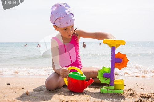 Image of A child plays with toys in the sand on the beach