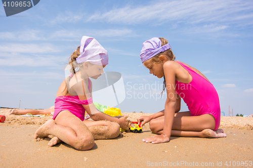 Image of Two children playing with toys in the sand on the sea beach