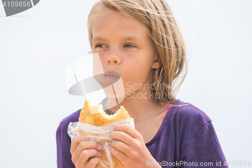 Image of A hungry girl with an appetite chews delicious cake on the beach
