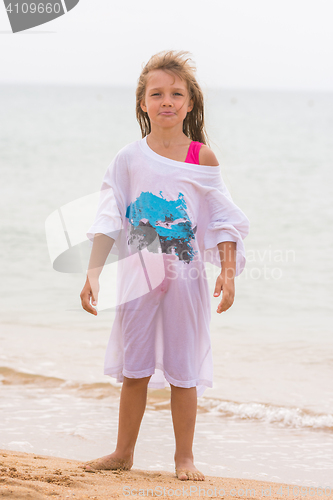 Image of Girl poses funny faces standing on the beach in my father\'s shirt