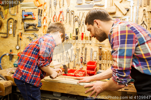 Image of father and son with hammer working at workshop