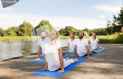 Image of group of people making yoga exercises outdoors