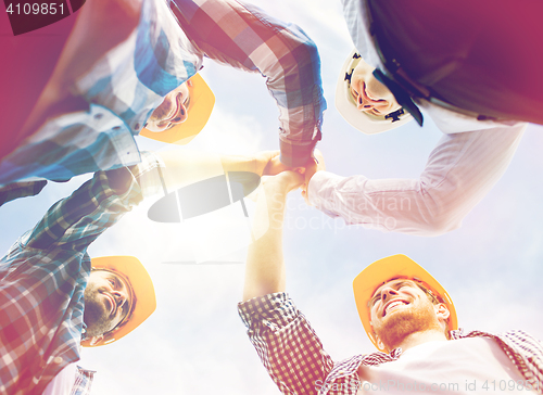 Image of close up of builders in hardhats making high five