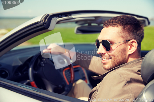 Image of happy man driving cabriolet car outdoors