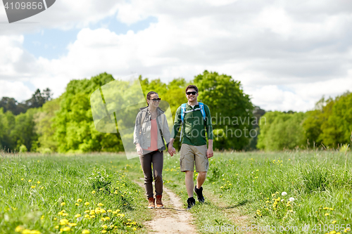 Image of happy couple with backpacks hiking outdoors