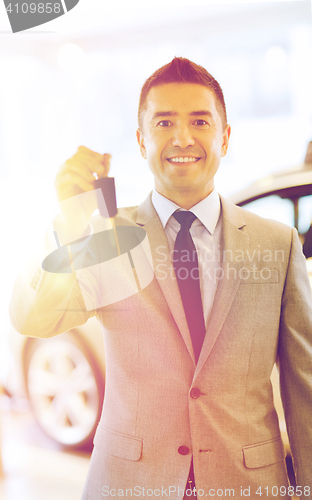 Image of happy man showing key at auto show or car salon