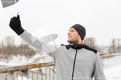 Image of man taking selfie with smartphone in winter 