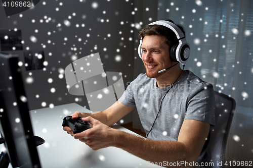 Image of man in headset playing computer video game at home