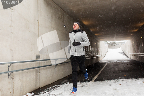 Image of happy man running along subway tunnel in winter